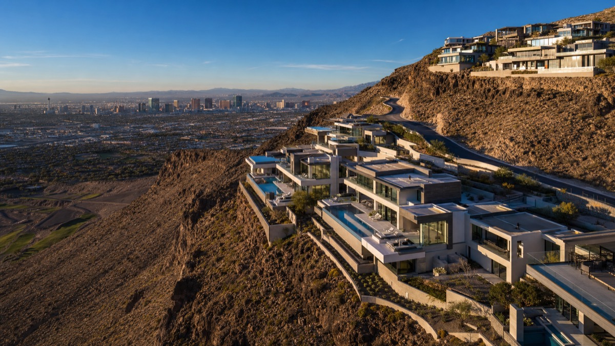 Aerial view of Ascaya in Henderson showing architect-designed custom homes stepped into the hillside, several with detached casita structures and resort pools visible in the rear yards — representative of the upper-tier multi-generational inventory in southern Henderson
